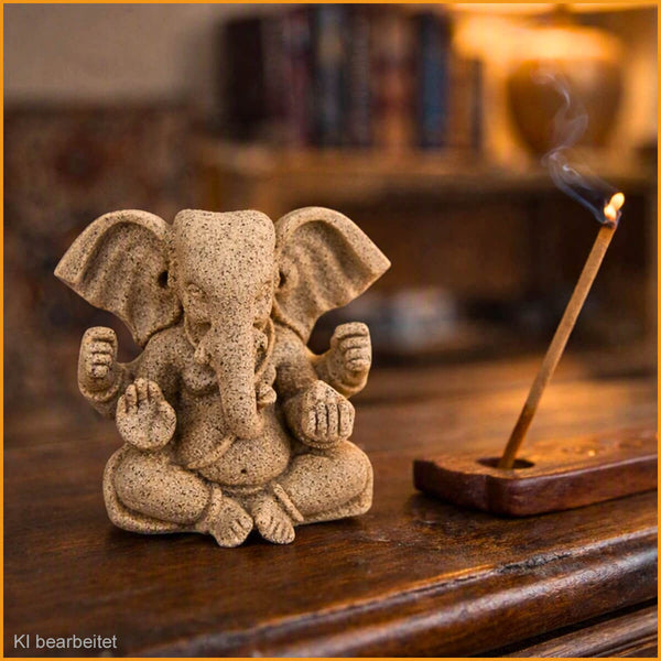 Kleine Ganesha-Skulptur aus Stein auf antiker Holzkommode, daneben brennendes Räucherstäbchen im Halter mit feinem Rauch – warme, gemütliche Wohnatmosphäre.